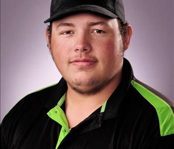 Male with brown hair wearing a SERVPRO Hat and black and green polo